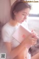 A woman sitting on a bed reading a book.