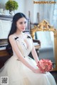 A woman in a wedding dress sitting next to a piano.