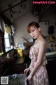 A woman in a floral dress standing in a kitchen.