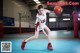 A young woman in a red and white uniform holding a basketball.