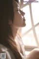 A woman sitting in front of a window with her eyes closed.