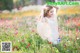 A woman in a white dress standing in a field of flowers.