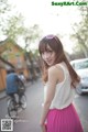 A woman in a pink skirt is standing on the street.