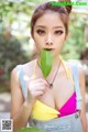 A woman in overalls holding a green leaf in her mouth.