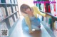 A woman crouching down in front of a bookshelf full of books.