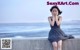 A woman sitting on a concrete wall by the ocean.