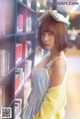 A woman standing in front of a bookshelf holding a book.