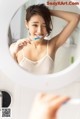 A woman brushing her teeth in front of a mirror.