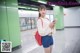 A woman standing in a subway station holding a book.