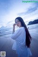 A woman standing on a beach next to the ocean.