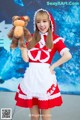 A woman in a red and white dress holding a teddy bear.