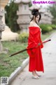 A woman in a red dress holding a sword.