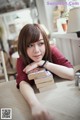 A woman sitting at a table with a stack of books.