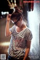 A woman wearing glasses leaning against a wall.