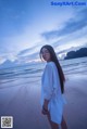 A woman standing on a beach next to the ocean.