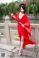 A woman in a red dress holding a sword.