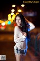 A woman in a white shirt and denim shorts posing for a picture.