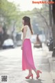 A woman in a pink skirt is walking down the street.