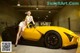 A woman sitting on top of a yellow sports car.