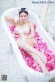 A woman in a bathtub filled with pink petals.