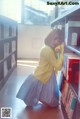 A young woman leaning against a bookshelf in a library.