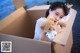 A woman holding a teddy bear in a cardboard box.