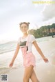 A woman standing on a beach next to the ocean.