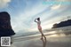 A woman in a pink dress standing on a beach.