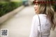 A woman in a white shirt is walking down the street.