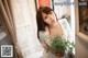 A woman holding a potted plant in front of a window.