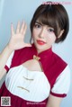 A woman in a red and white dress waving her hand.