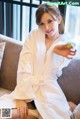 A woman in a white robe sitting on a couch.