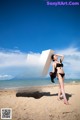 A woman in a black bikini standing next to a large letter W.