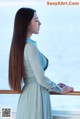 A woman with long brown hair standing on a balcony.