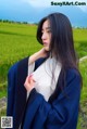 A woman in a blue kimono standing in a field.