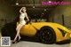 A woman sitting on top of a yellow sports car.