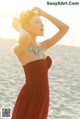 A woman in a red dress standing on a beach.