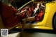 A woman sitting in the driver's seat of a yellow sports car.