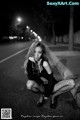 A woman sitting on the side of a road at night.