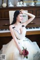 A woman in a wedding dress sitting on a piano.