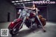 A woman sitting on a red motorcycle in a garage.