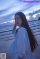 A woman standing on a beach next to the ocean.