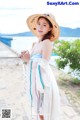 A woman in a straw hat standing on a beach.