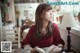 A woman sitting at a table reading a book.