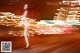 A woman in a pink dress standing on a street at night.