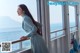 A woman in a blue dress standing on a boat looking out the window.