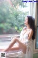 A woman sitting on a window sill in a white lingerie.