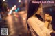 A woman standing in the middle of a city at night.