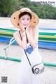 A woman in a white dress and a straw hat posing for a picture.