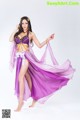 A woman in a purple belly dance outfit is posing for a picture.